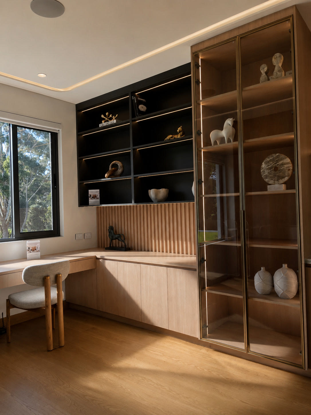 Study nook with a built-in desk, timber joinery, black open shelving and a glass-fronted display cabinet