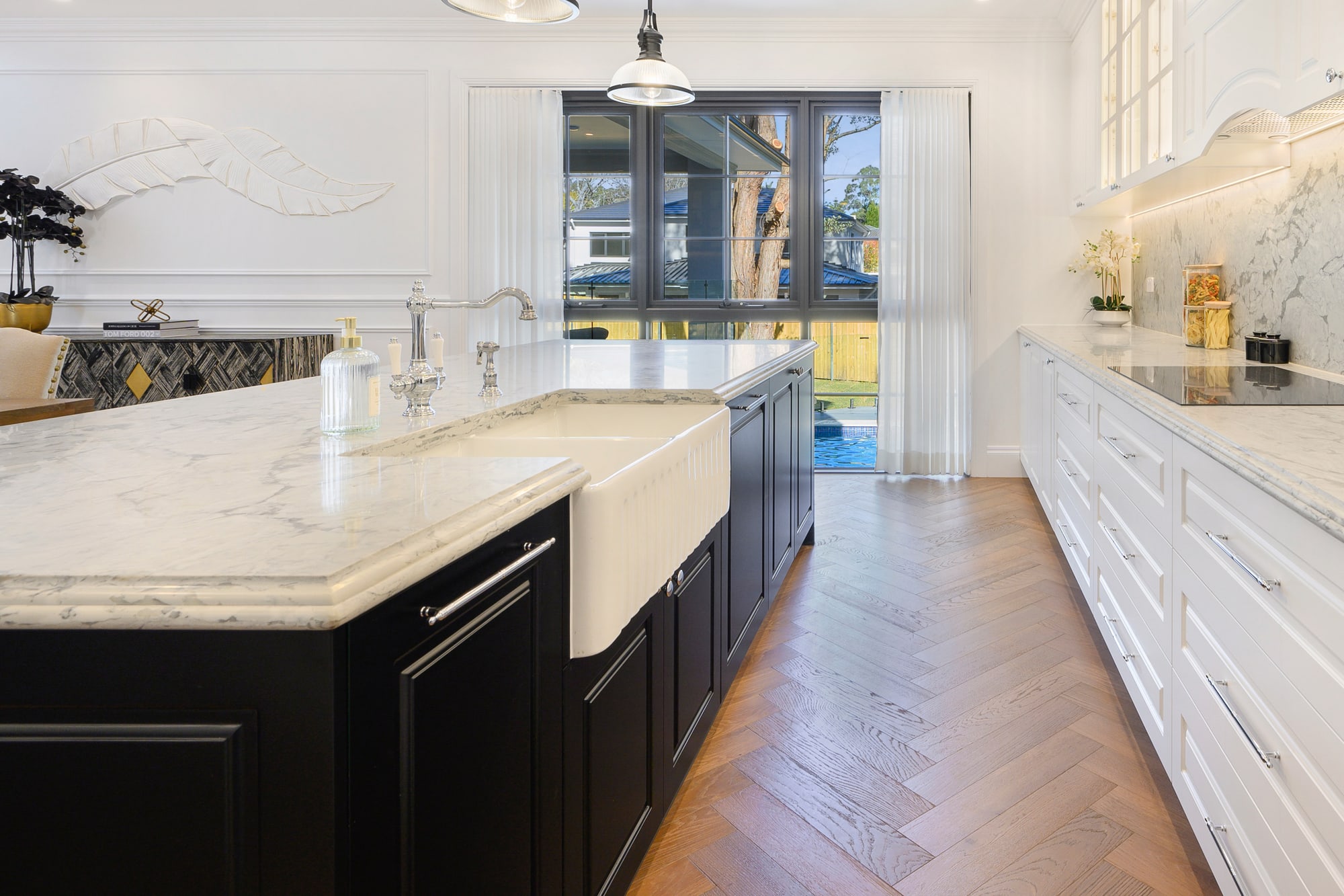 Marble kitchen island with black base cabinets and industrial pendant lights