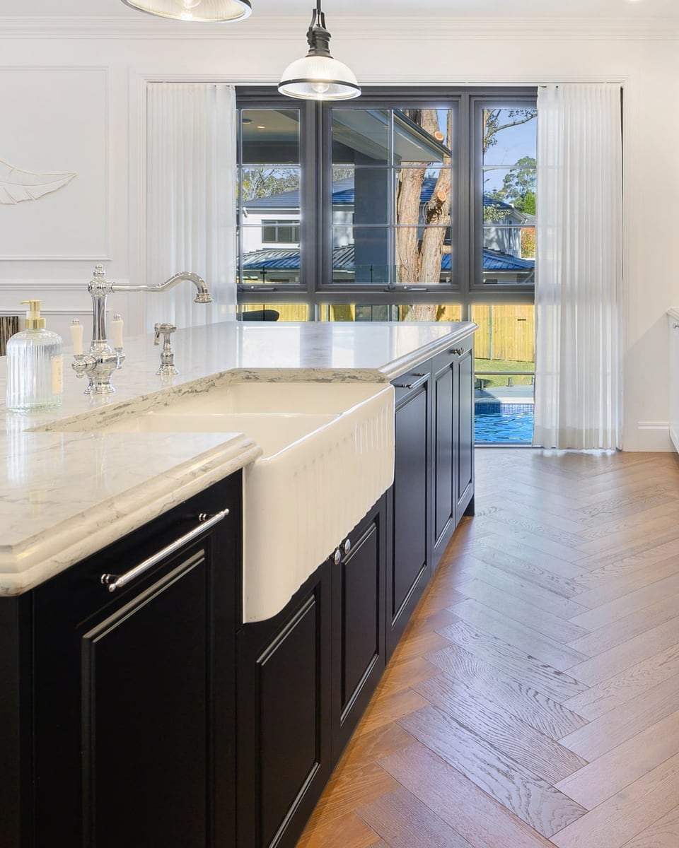 Marble kitchen island with black base cabinets and industrial pendant lights