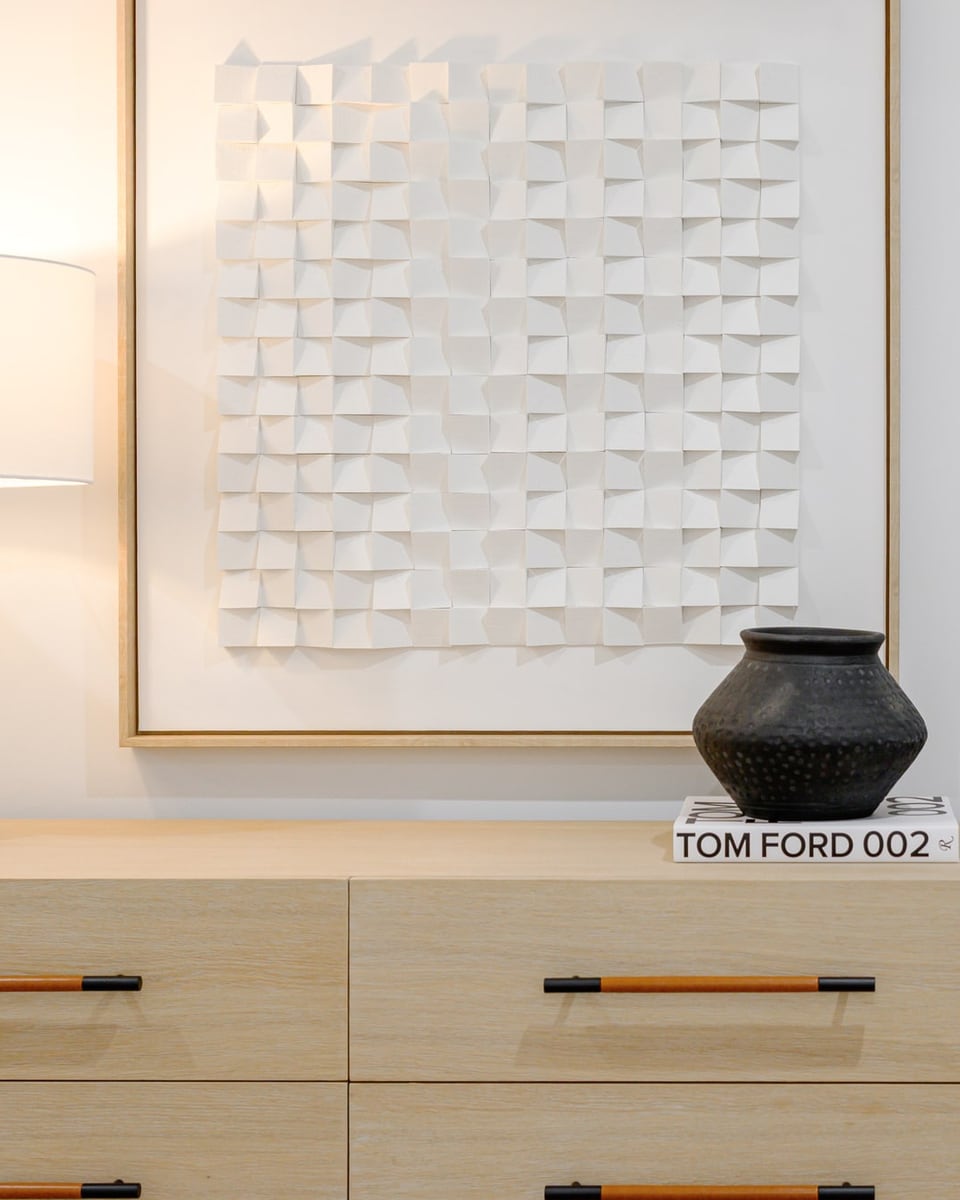 Pale timber entry console styled with a table lamp, a framed textured artwork and a black vase