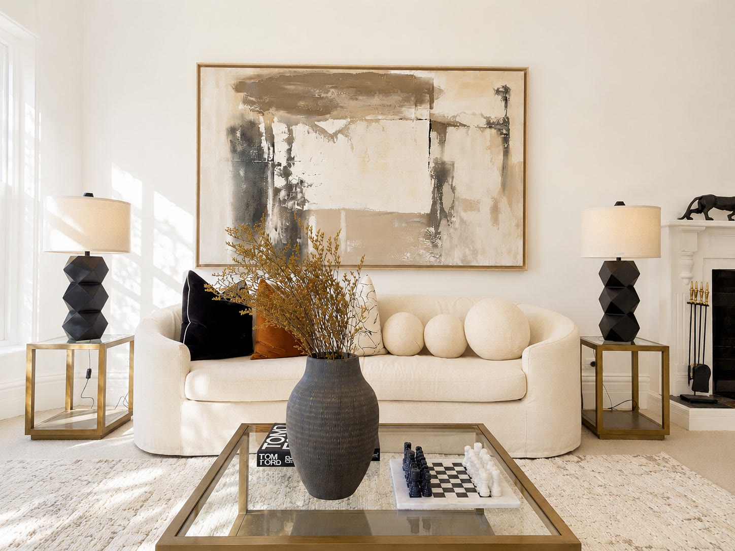 Cream sofa with round cushions, sculptural black lamps and a large abstract painting above