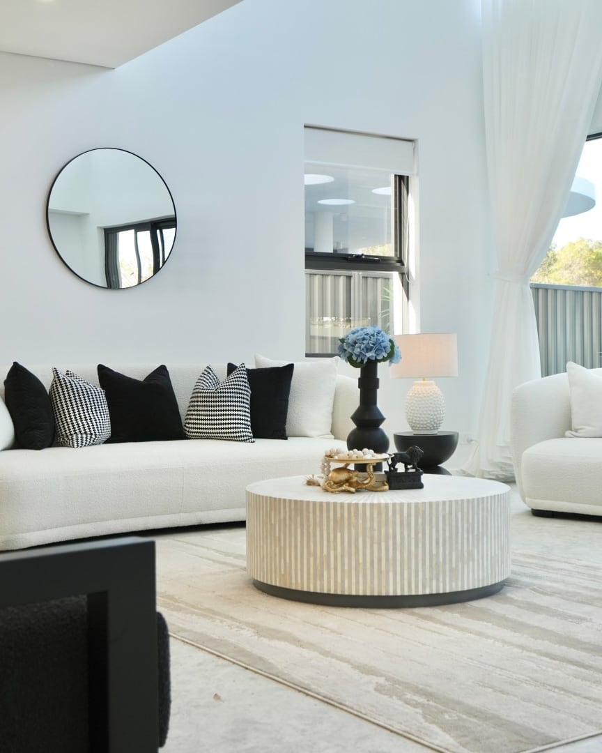 East Hills living room with curved white sofas, black and white cushions and a round mirror
