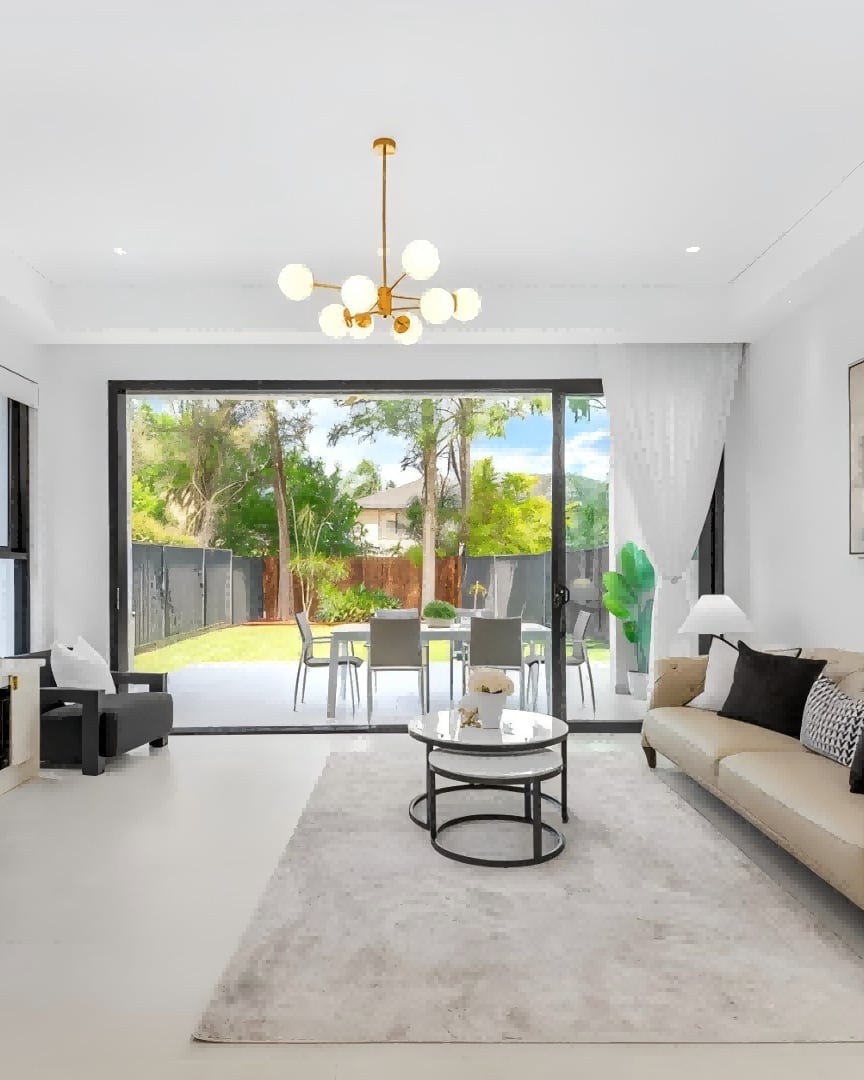 Padstow living room with a beige sofa and gold chandelier opening onto a garden dining area