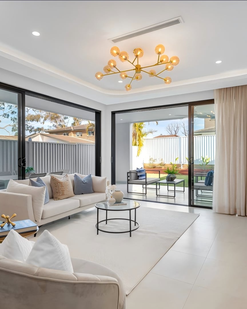 Revesby open living room with cream sofas, a gold chandelier and doors to the alfresco