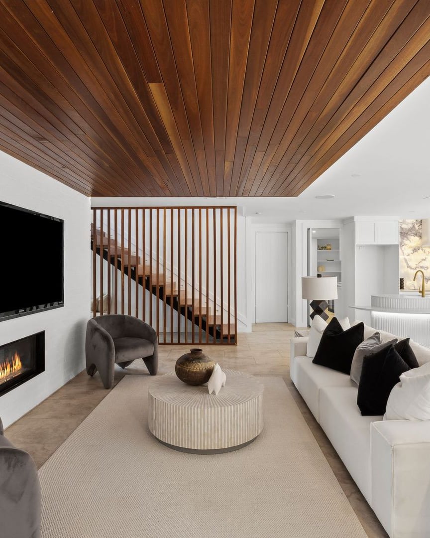 Turramurra living room under a timber ceiling, with a white sofa, velvet armchairs and a fireplace