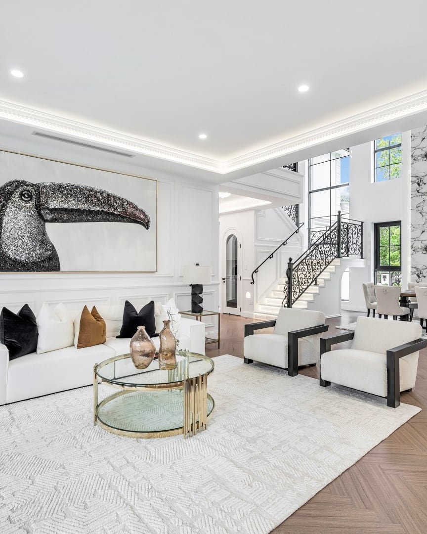 West Pymble living and dining area with a white sofa, gold coffee table and statement staircase