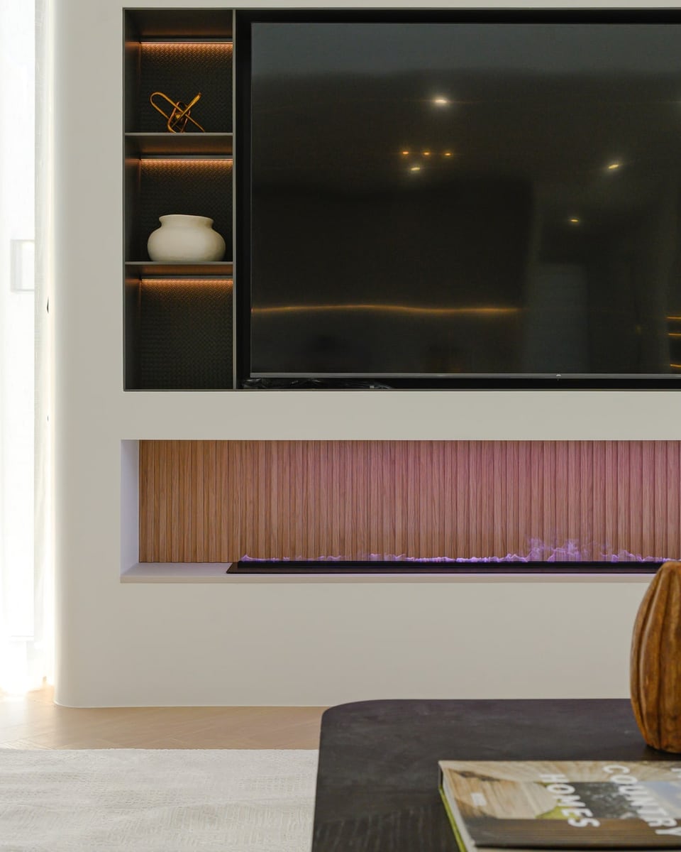 Feature wall with a built-in television and fireplace, wooden vases and a cream sofa with mustard cushions