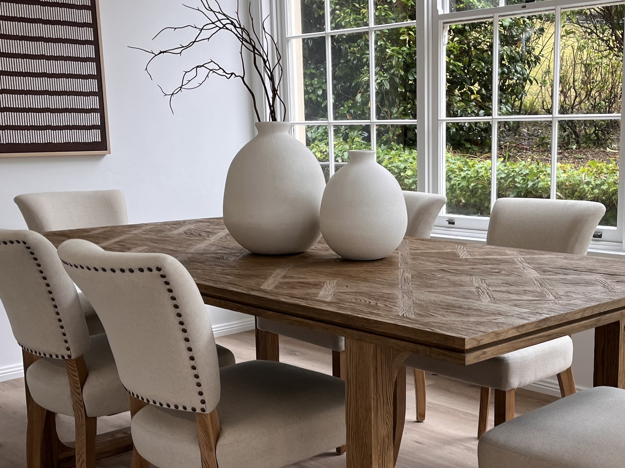 Parquet-top dining table with white vases and branches as a centrepiece