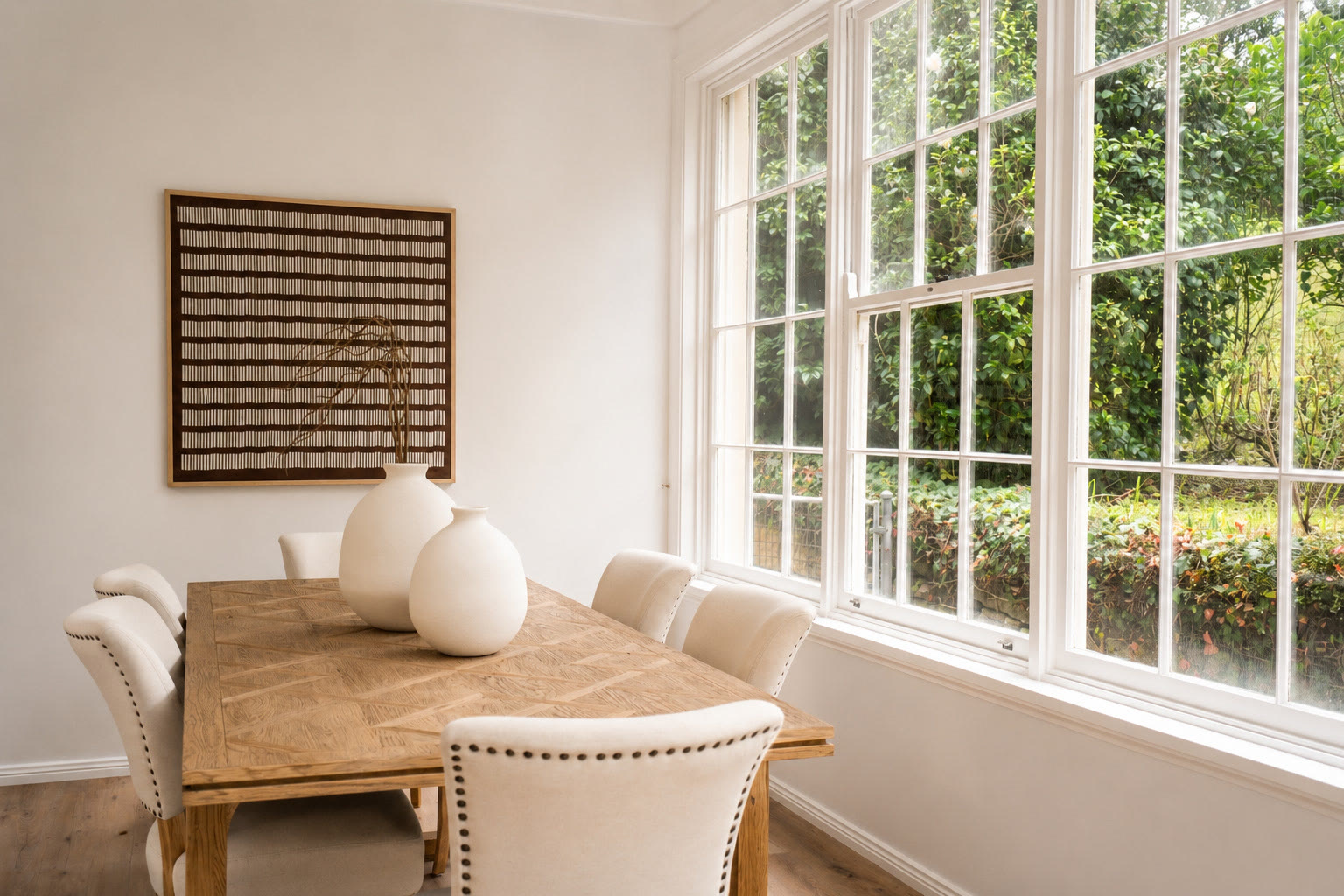 Dining table with a framed striped artwork and a large window onto the garden