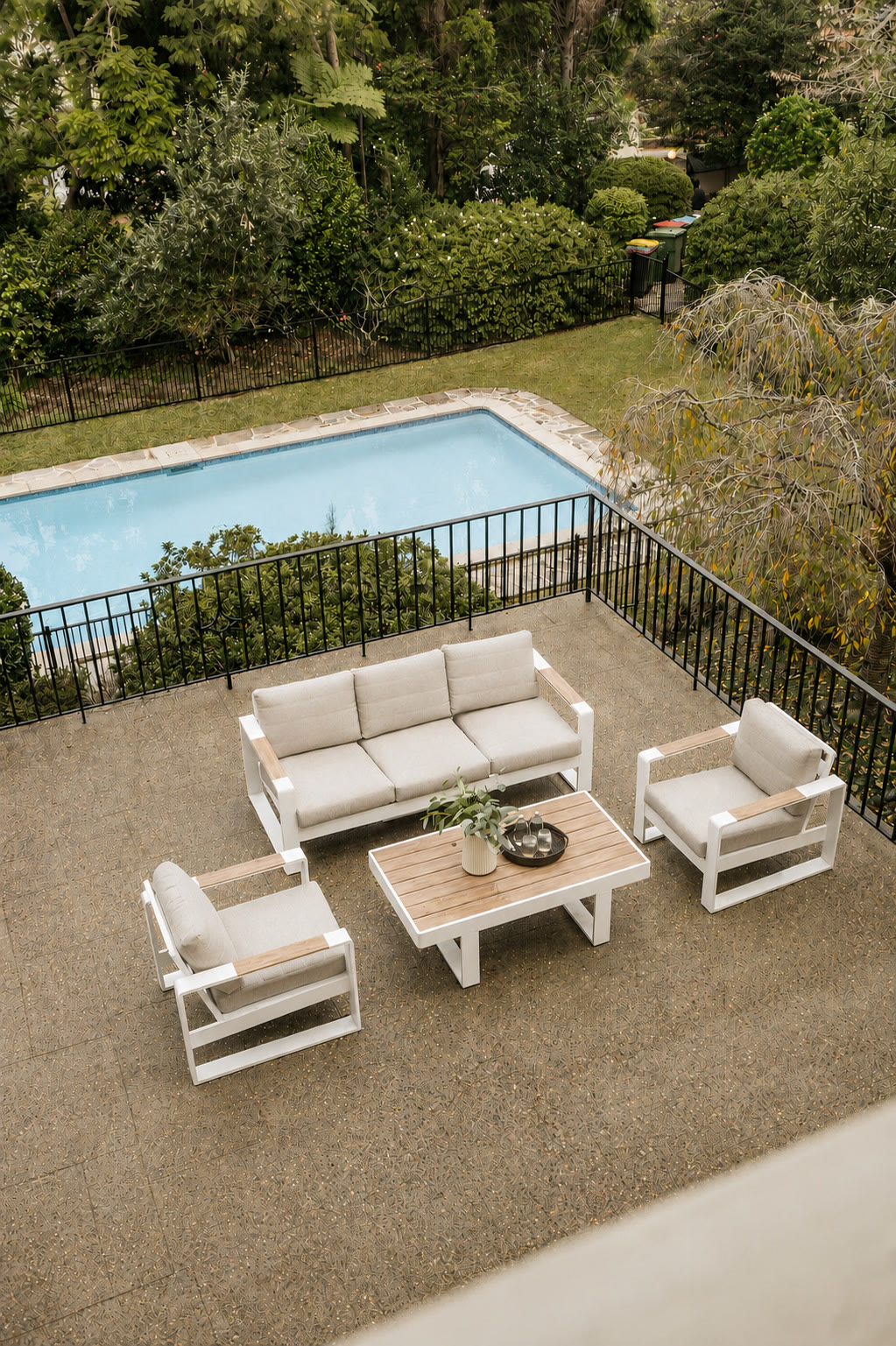Garden pool and outdoor lounge setting viewed from a balcony