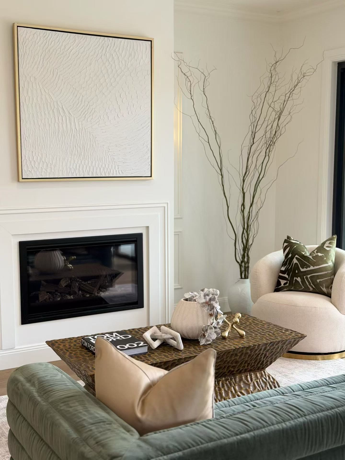 Living room with a recessed fireplace, a textured white artwork, a dark timber coffee table and a green velvet sofa