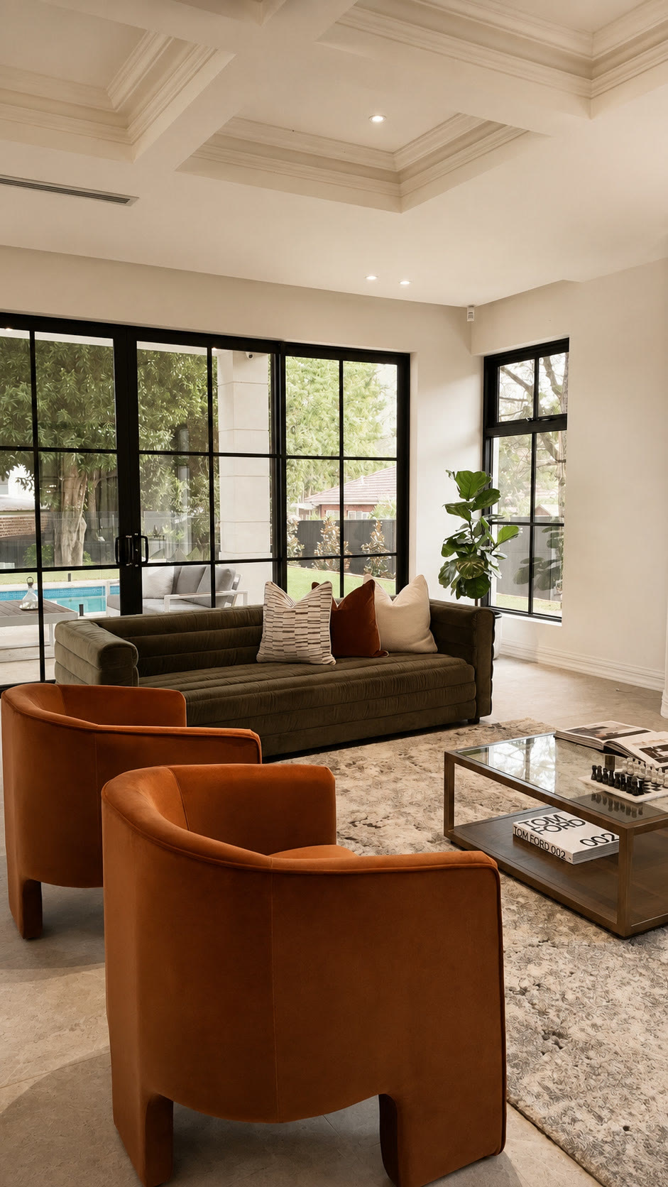 Living room corner with rust velvet armchairs, a green sofa and a glass-topped coffee table
