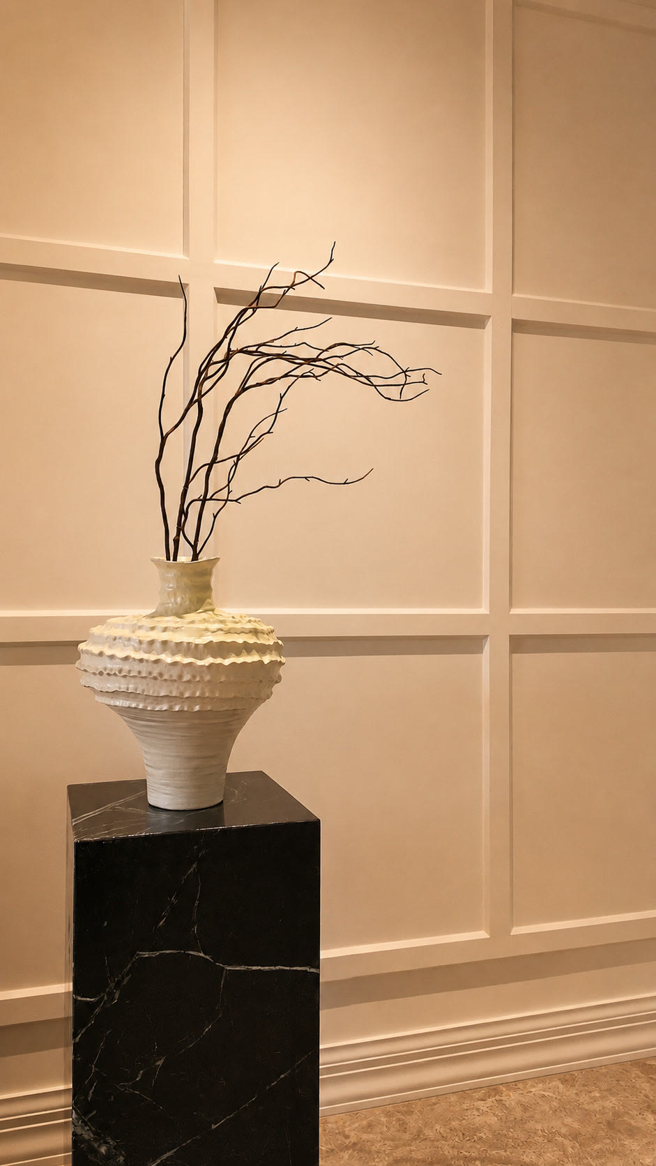 White textured vase with dried branches on a black marble plinth
